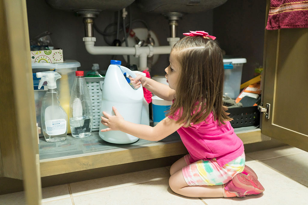 Little kid removing container from cabinet in kitchen at home