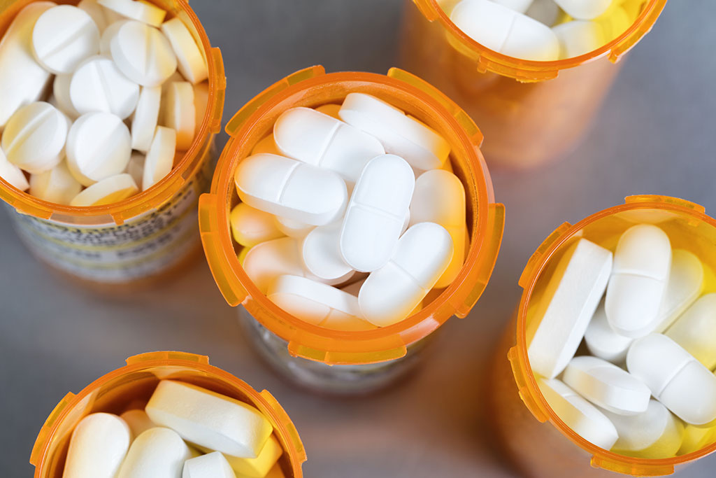 Close up overhead view of full prescription bottles on stainless steel background